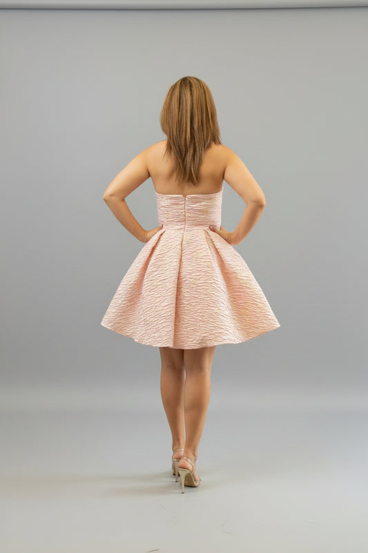 Woman trying on a pink dress in front of a mirror.