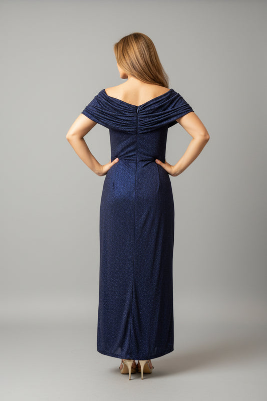 Woman in a navy blue dress standing in front of a mirror in an elegant room.