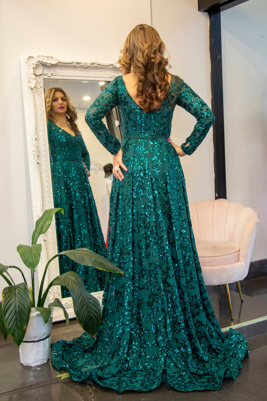 Woman in a green sequined dress standing in front of a mirror.