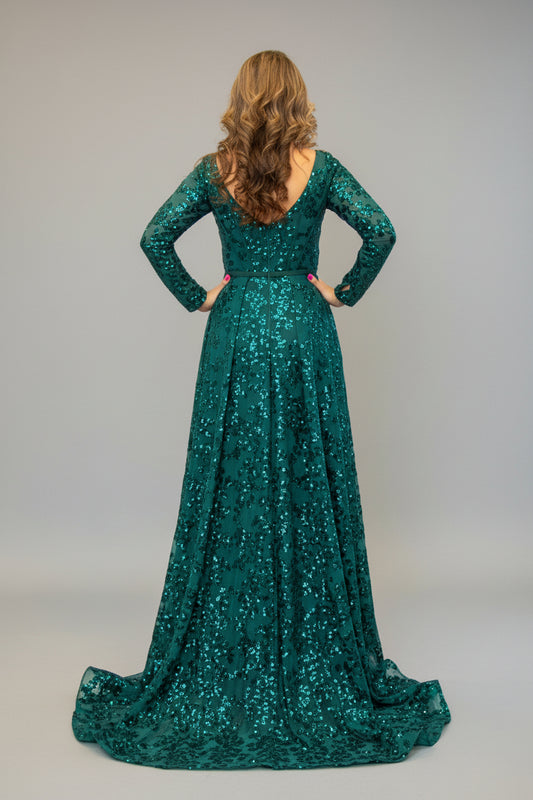 Woman in a green sequined dress standing in front of a mirror.