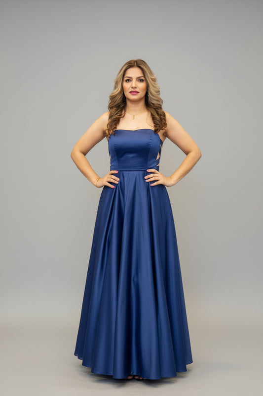 Woman in a blue evening gown standing in front of a mirror.