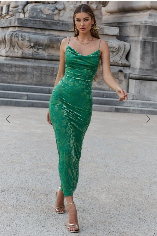 Woman in a green dress standing in front of stone architectural elements
