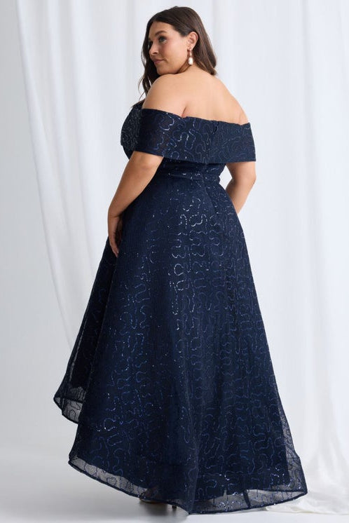 Woman wearing a navy off-shoulder gown against a white background