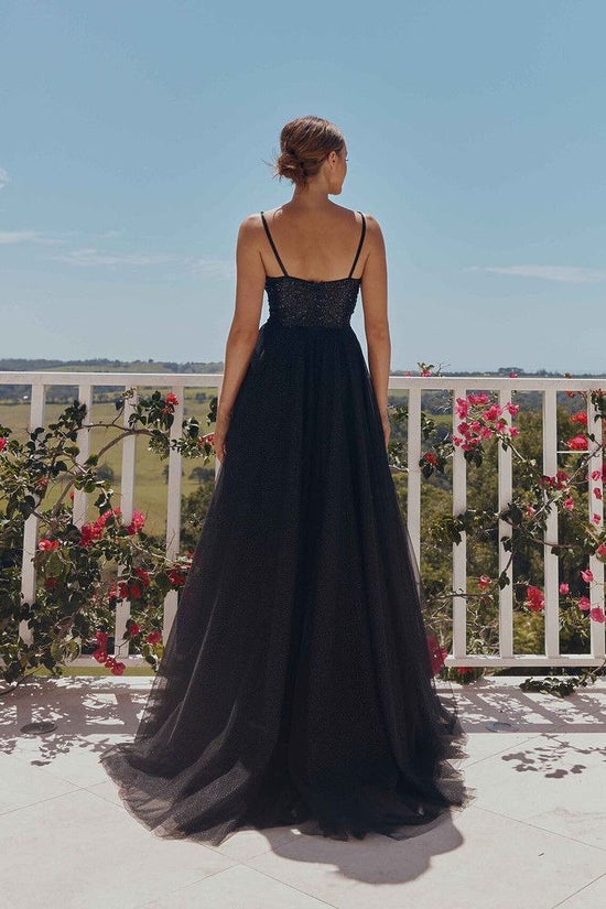Woman in a black evening gown standing on a balcony with floral decorations.