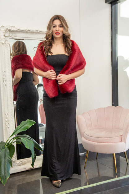 Woman wearing a red shawl over a black dress in front of a mirror.