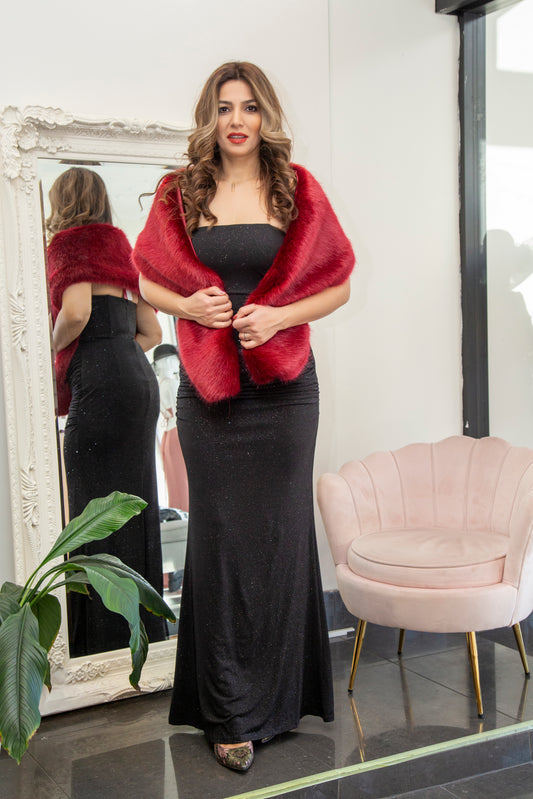 Woman wearing a red shawl over a black dress in front of a mirror.