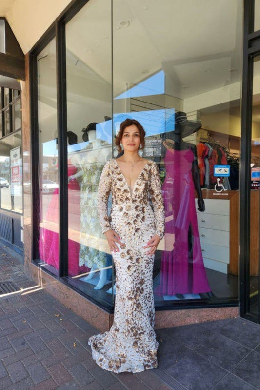 Woman in a white lace dress standing in front of a store window display.