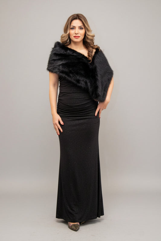 Woman wearing a black dress with a fur shrug in front of a mirror.