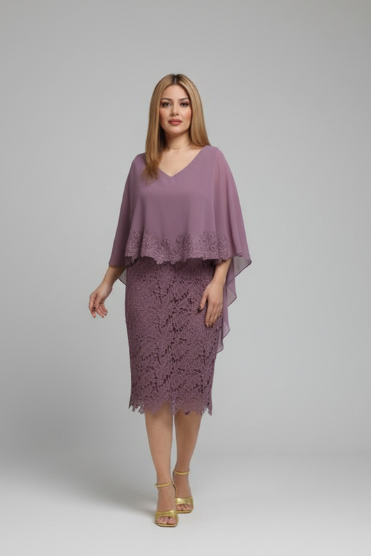 A woman modeling a mauve purple 0ne-piece outfit consisting of a V-neck sheer cape top and a matching lace pencil skirt, paired with gold platform sandals, against a neutral gray studio background.