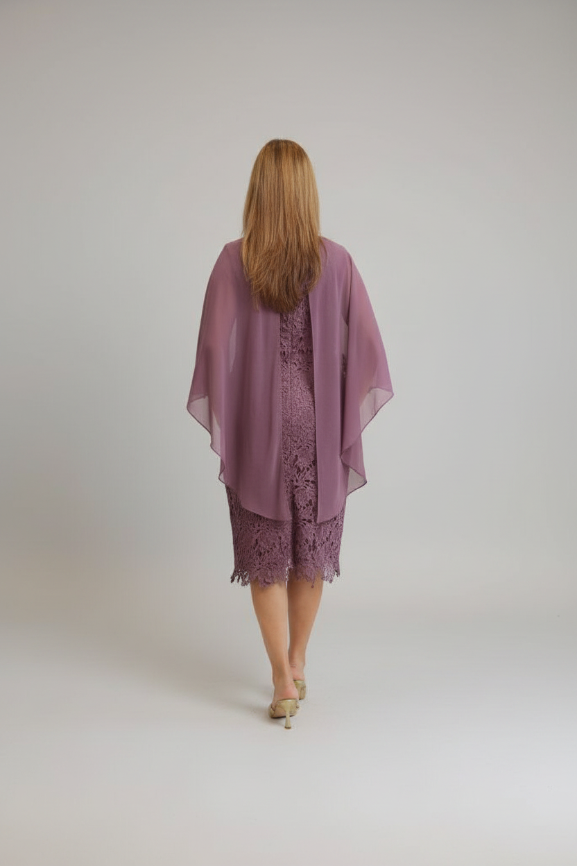 A woman viewed from behind wearing a mauve purple sheer open-front shawl over a matching lace dress, standing against a plain light gray studio background.