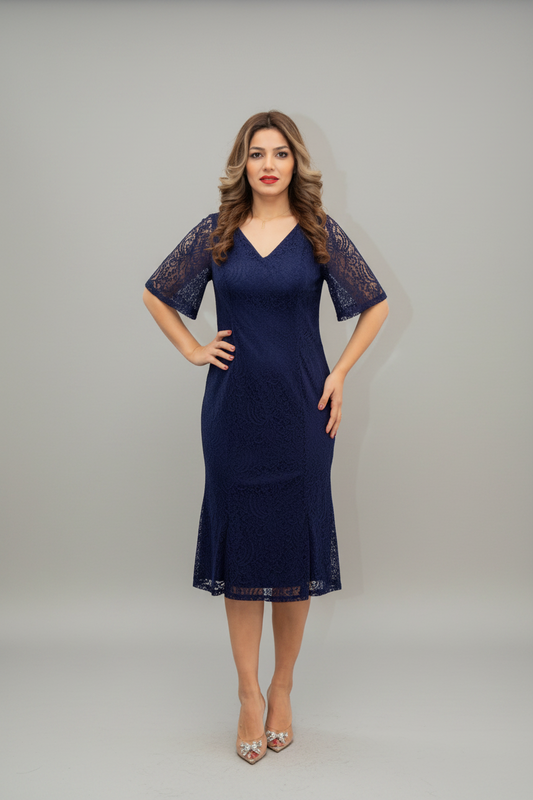 A woman modeling a navy blue lace midi dress with short sleeves and a V-neckline, standing against a plain light gray studio background.