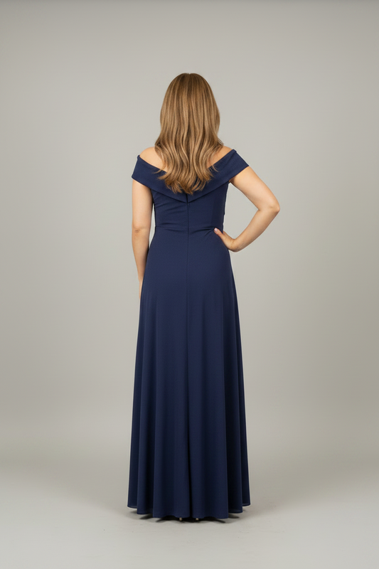 Woman in a long navy dress looking at herself in a mirror.