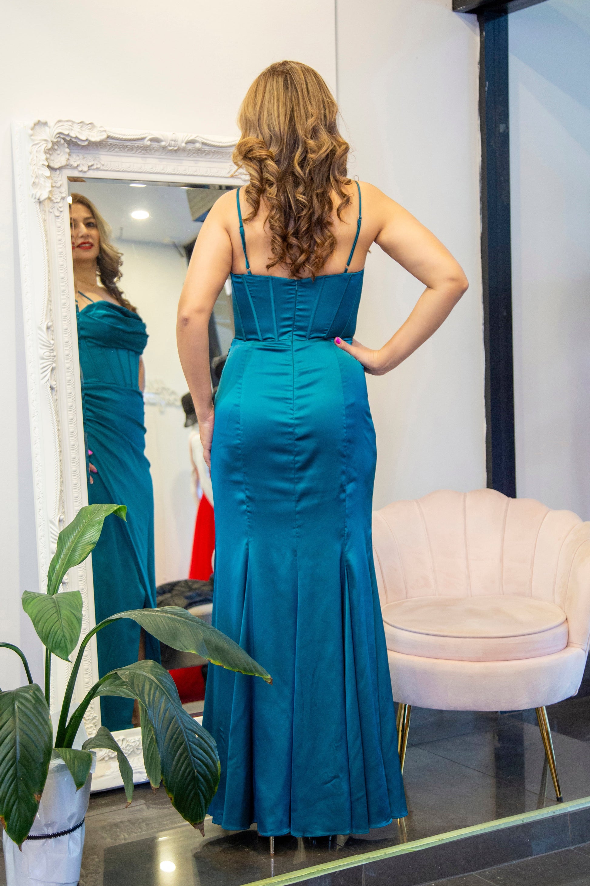 Woman in a blue evening gown standing in front of a mirror.