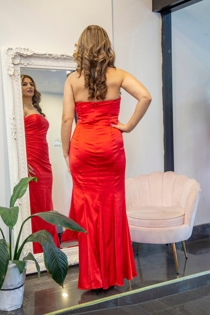 Woman in a red strapless gown standing in front of a mirror.
