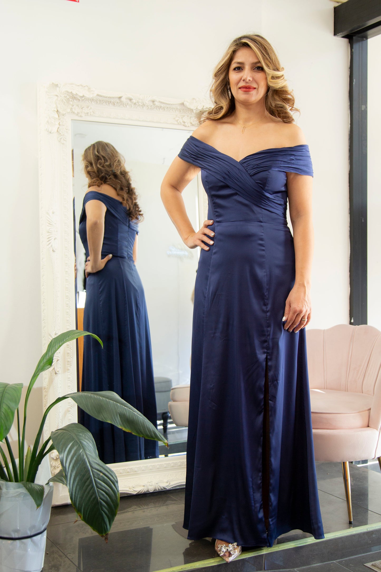 Woman in a blue evening gown standing in front of a mirror.