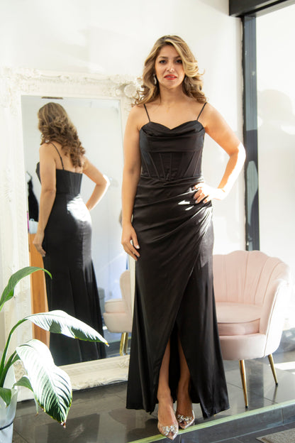 Woman in a black evening gown standing in front of a mirror.