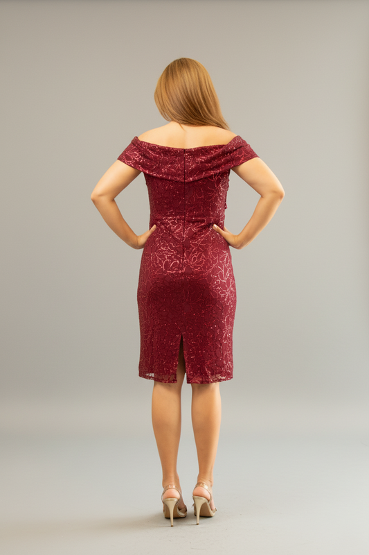 Woman in a burgundy dress standing in front of a mirror in a room with a pink chair and plant.