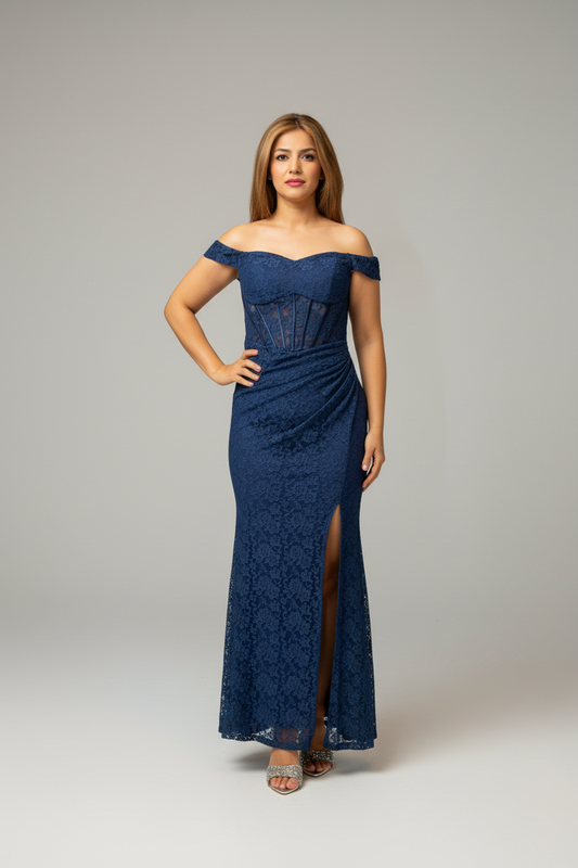 Woman in a blue lace dress standing in front of a mirror in a room with a chair and plant.