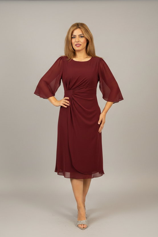 Woman wearing a red dress with sheer sleeves on a plain background