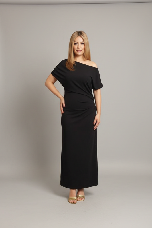 A woman modeling a black off-the-shoulder maxi dress with short sleeves and a gathered waist, standing against a neutral gray studio background.