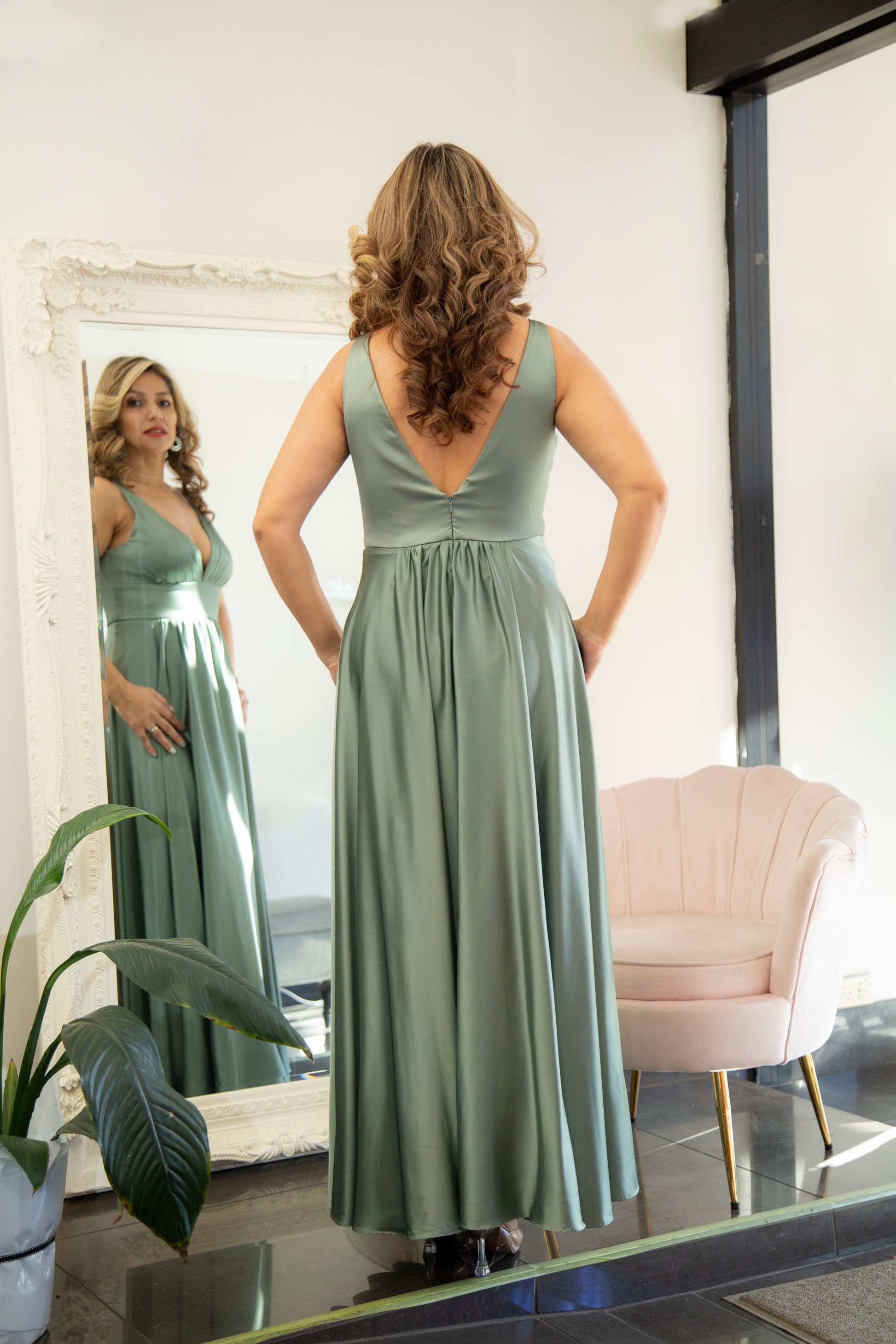 Woman in a long green dress standing in front of a mirror.