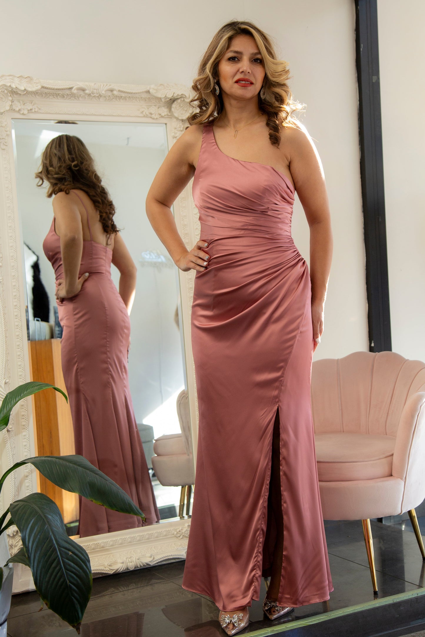Woman in a pink evening gown standing in front of a mirror.