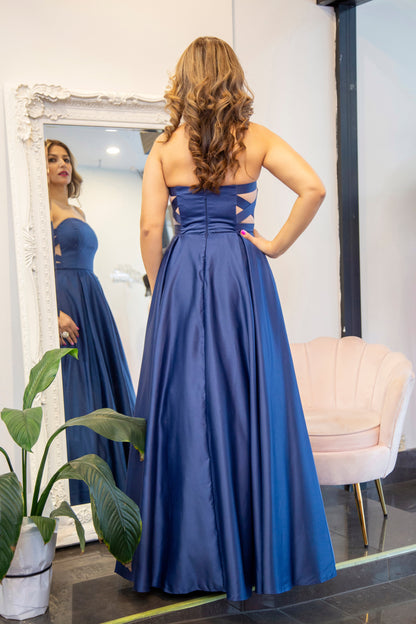 Woman wearing a blue evening gown standing in front of a mirror.