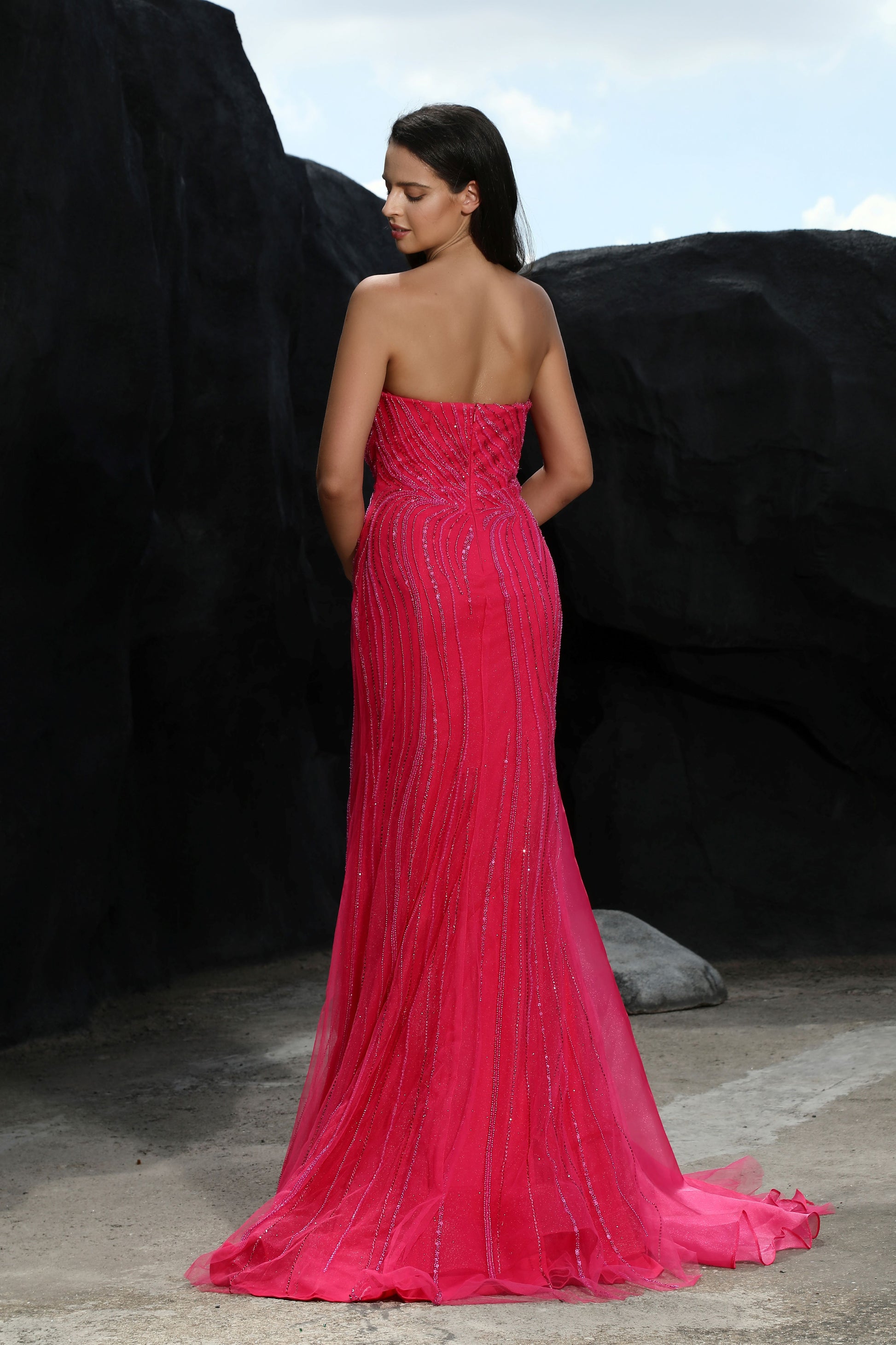 Woman in a pink evening gown standing against a dark background