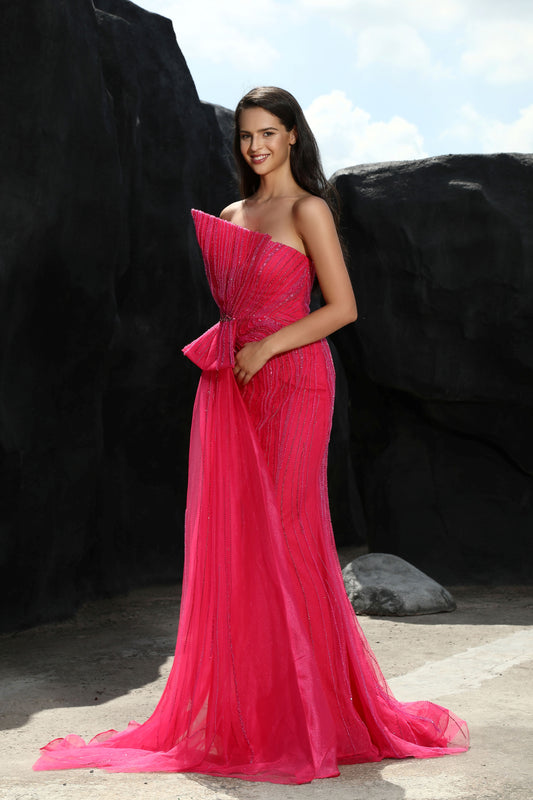 Woman in a pink dress standing against a black rocky background