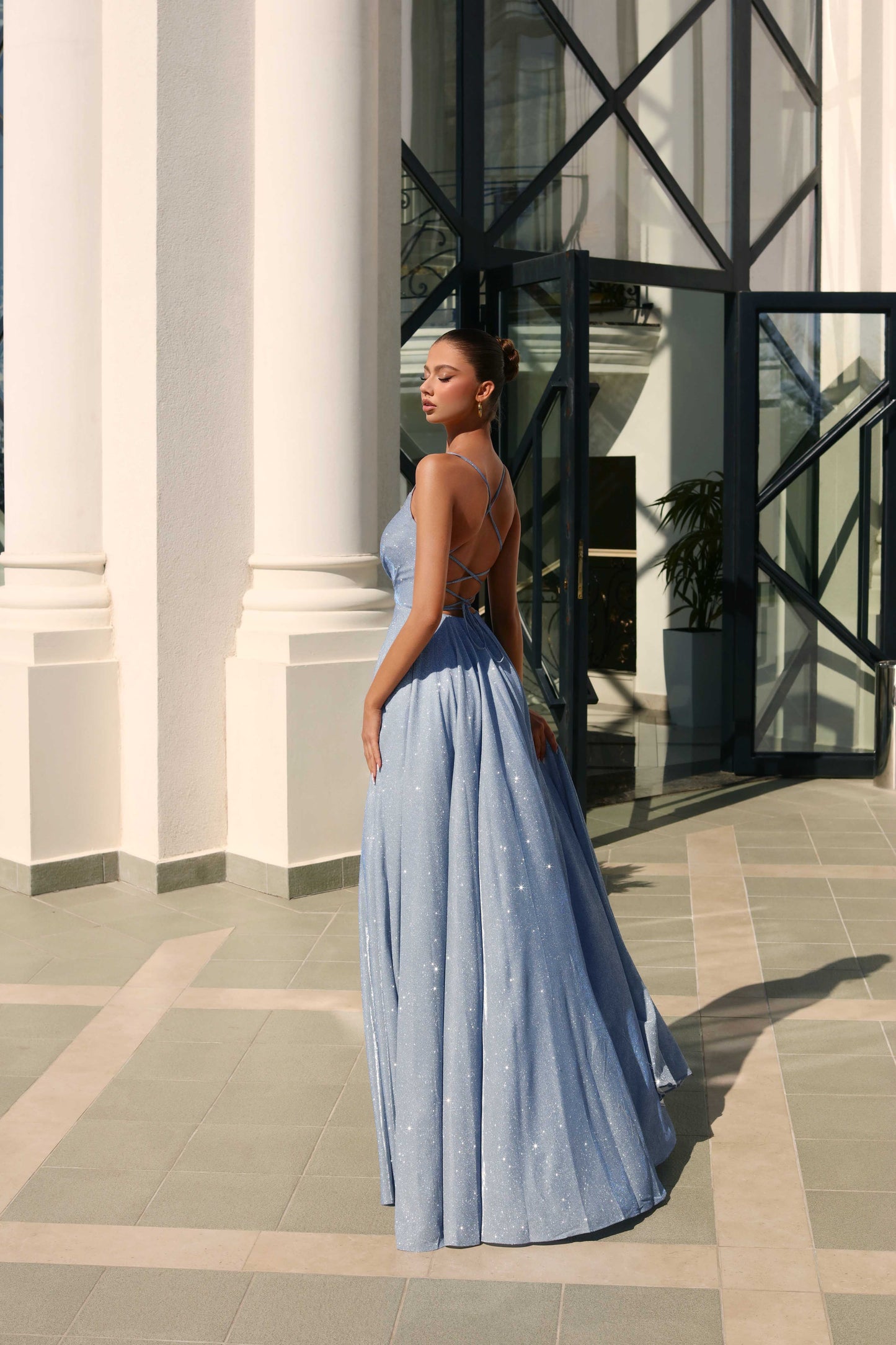 Woman in a blue evening gown standing in front of classical architecture