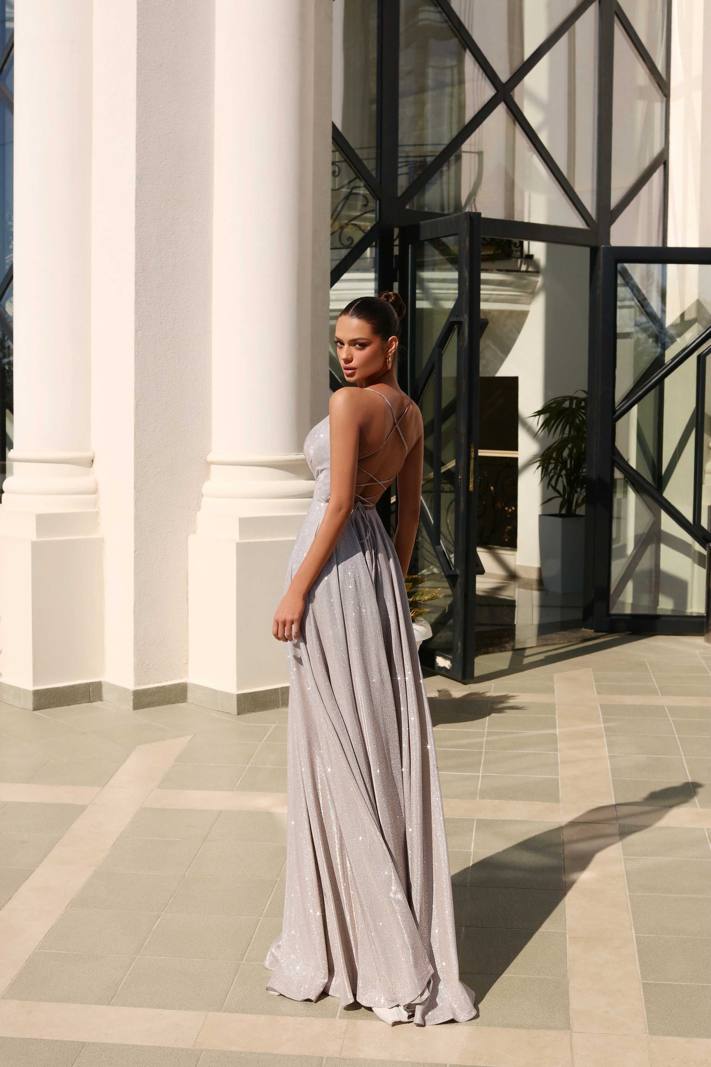 Woman in a long, light-colored dress standing in front of a classical building with columns.