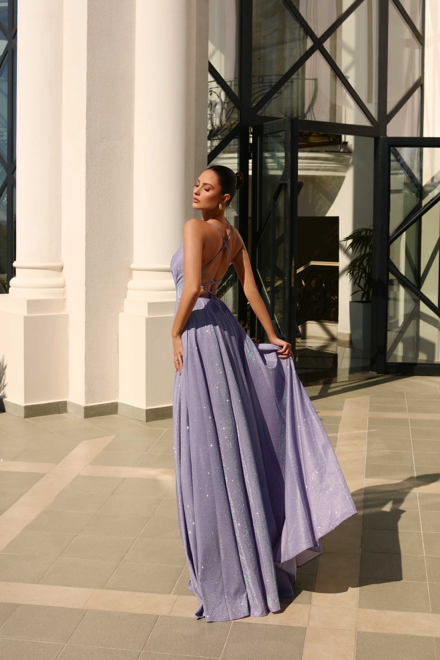 Woman in a long, light purple dress standing in front of a building entrance.