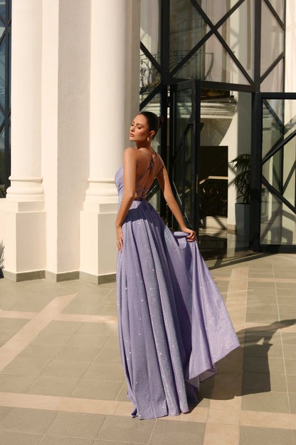 Woman in a long, light purple dress standing in front of a building entrance.