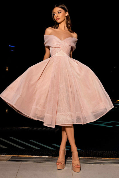 Woman in a pink off-shoulder dress standing on a street at night.