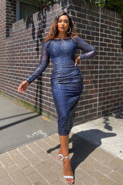 Woman in a blue sequin dress walking on a sidewalk with a brick wall background