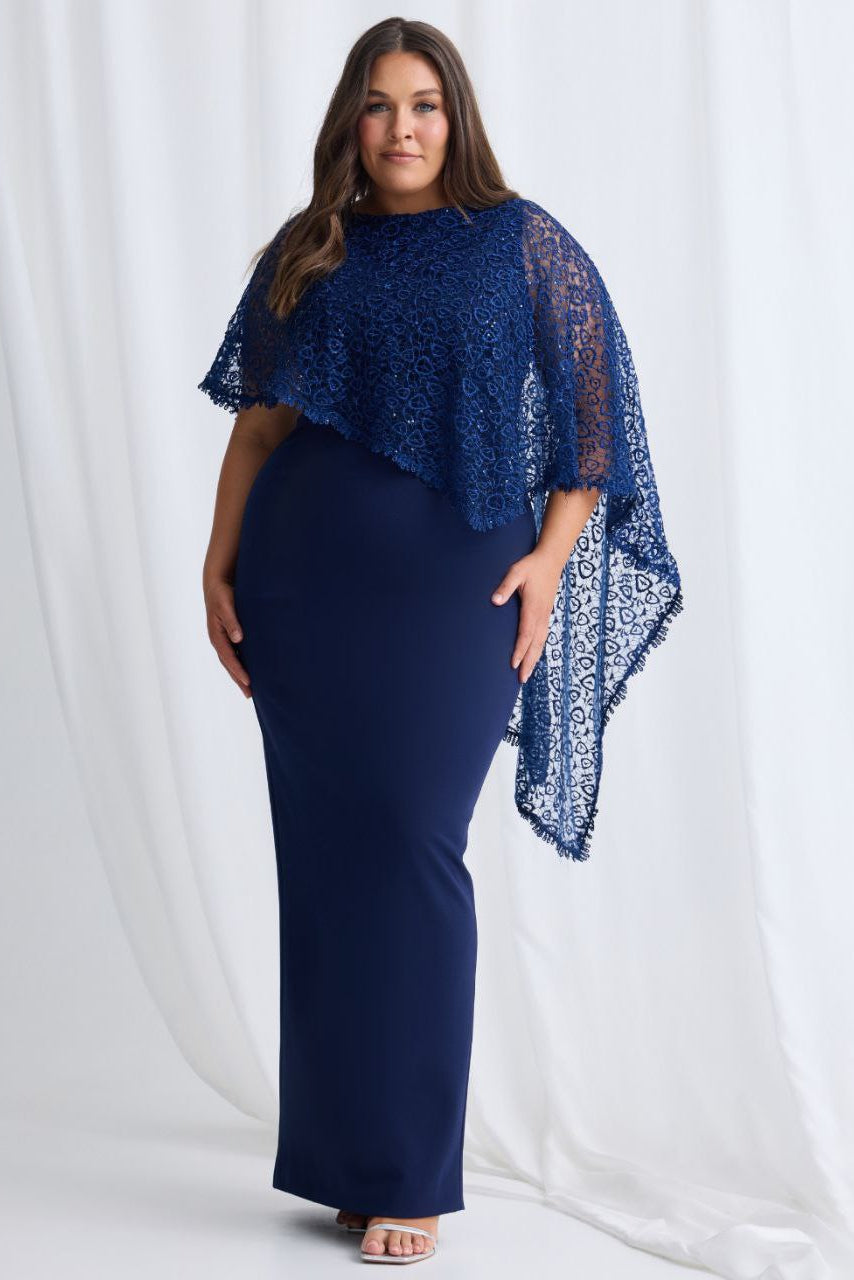 Woman wearing a navy blue dress with lace sleeves against a white background