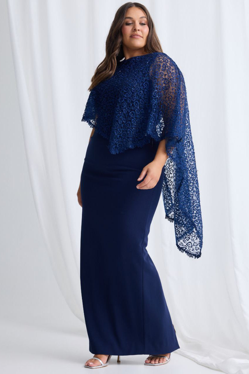 Woman wearing a navy blue dress with a matching lace shawl against a white background