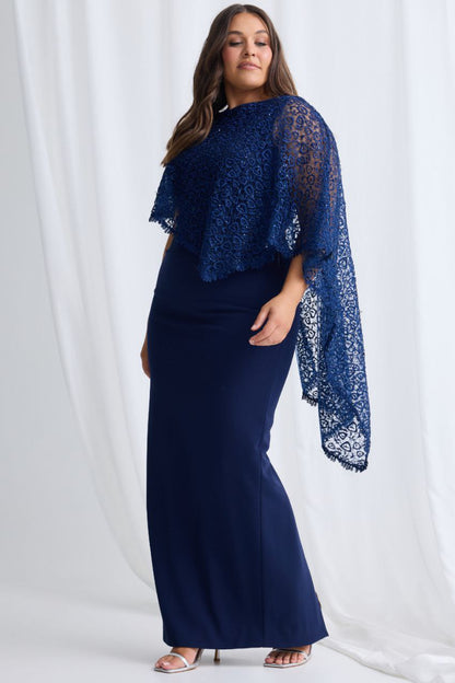 Woman wearing a navy blue dress with a matching lace shawl against a white background