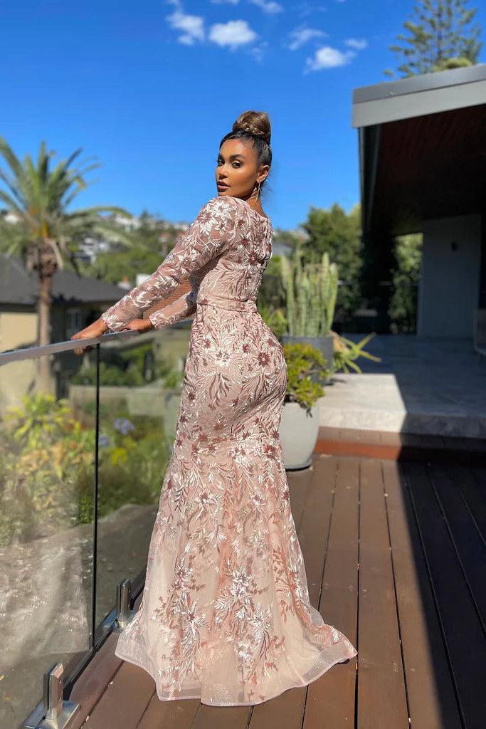 Woman in a floral dress standing on a wooden deck with a scenic background