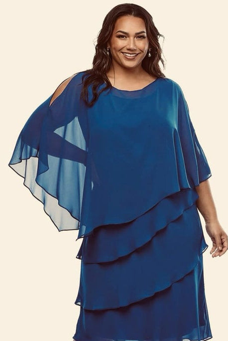 Woman wearing a blue layered dress with sheer sleeves on a beige background