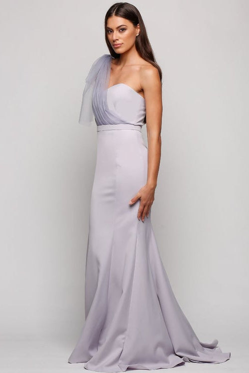 Woman wearing a one-shoulder lavender gown with a matching headscarf on a plain background