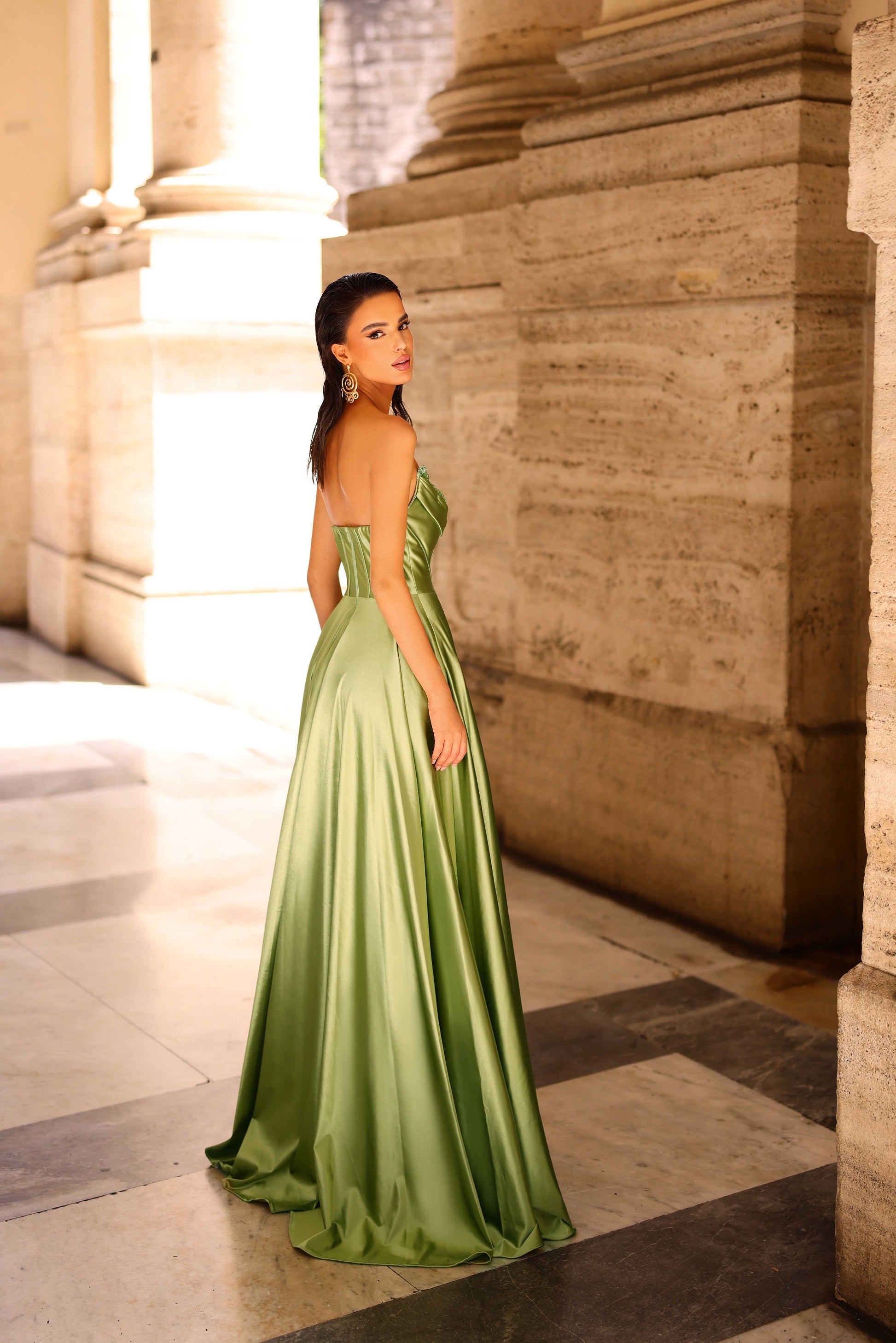 Woman in a green strapless gown standing in an architectural setting