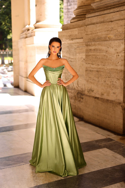 Woman in a green evening gown standing in front of classical architecture.