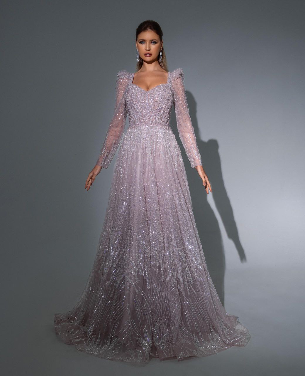 Woman wearing a glamorous pINK evening gown against a gray background