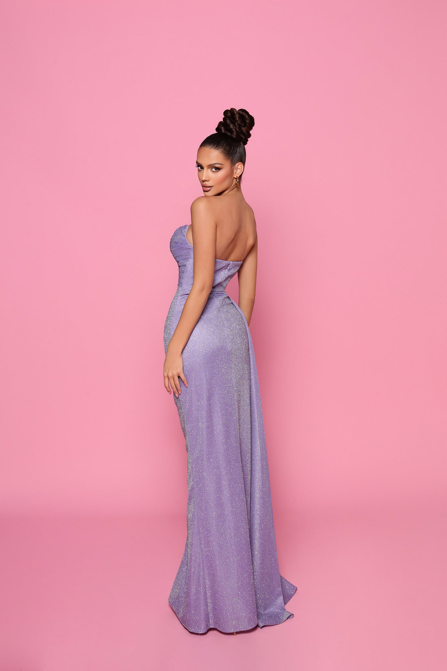 Woman in a purple evening gown against a pink background