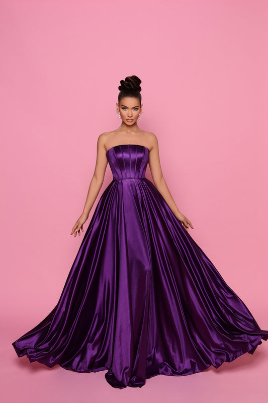 Woman wearing a purple strapless gown against a pink background