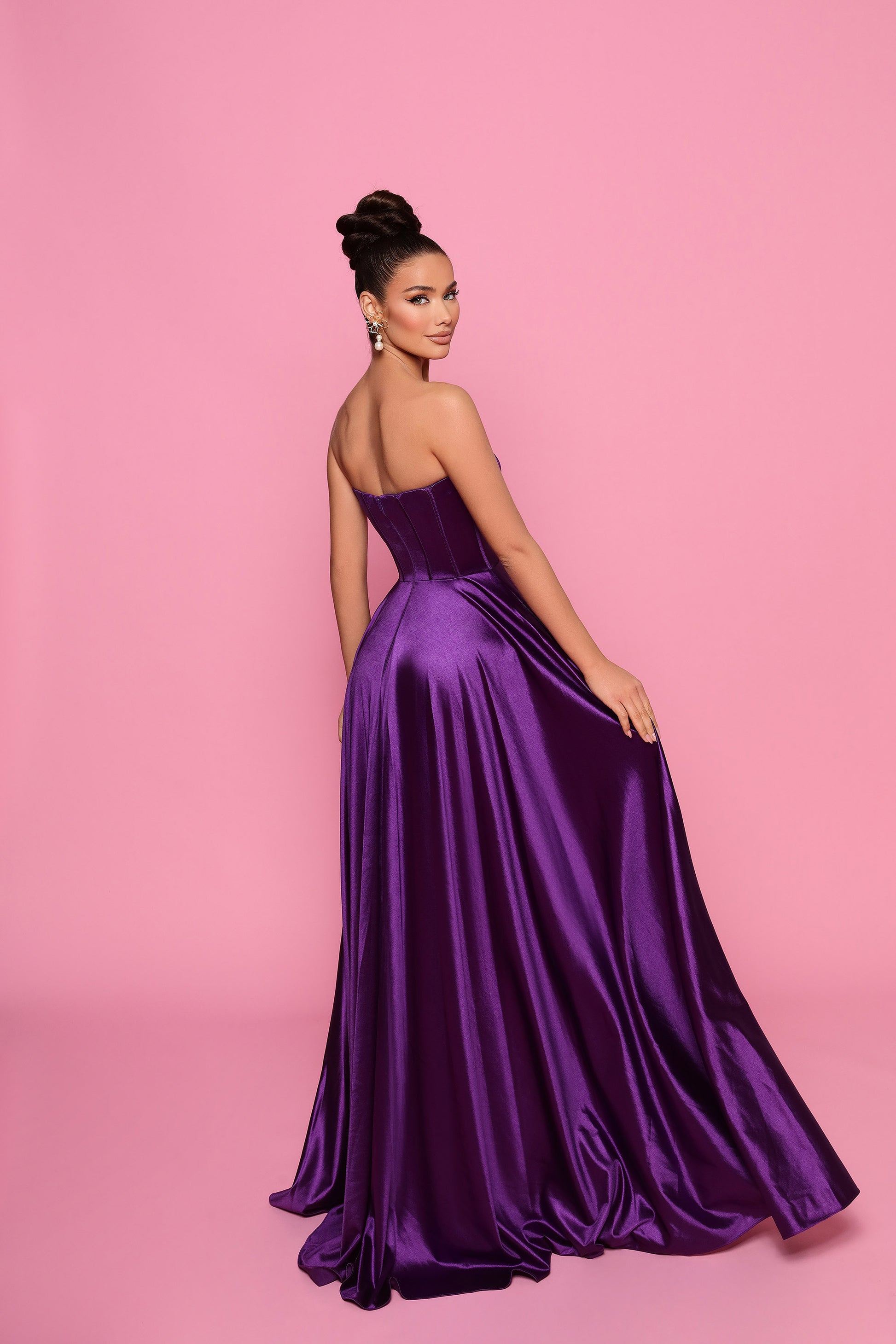 Woman wearing a purple evening gown against a pink background