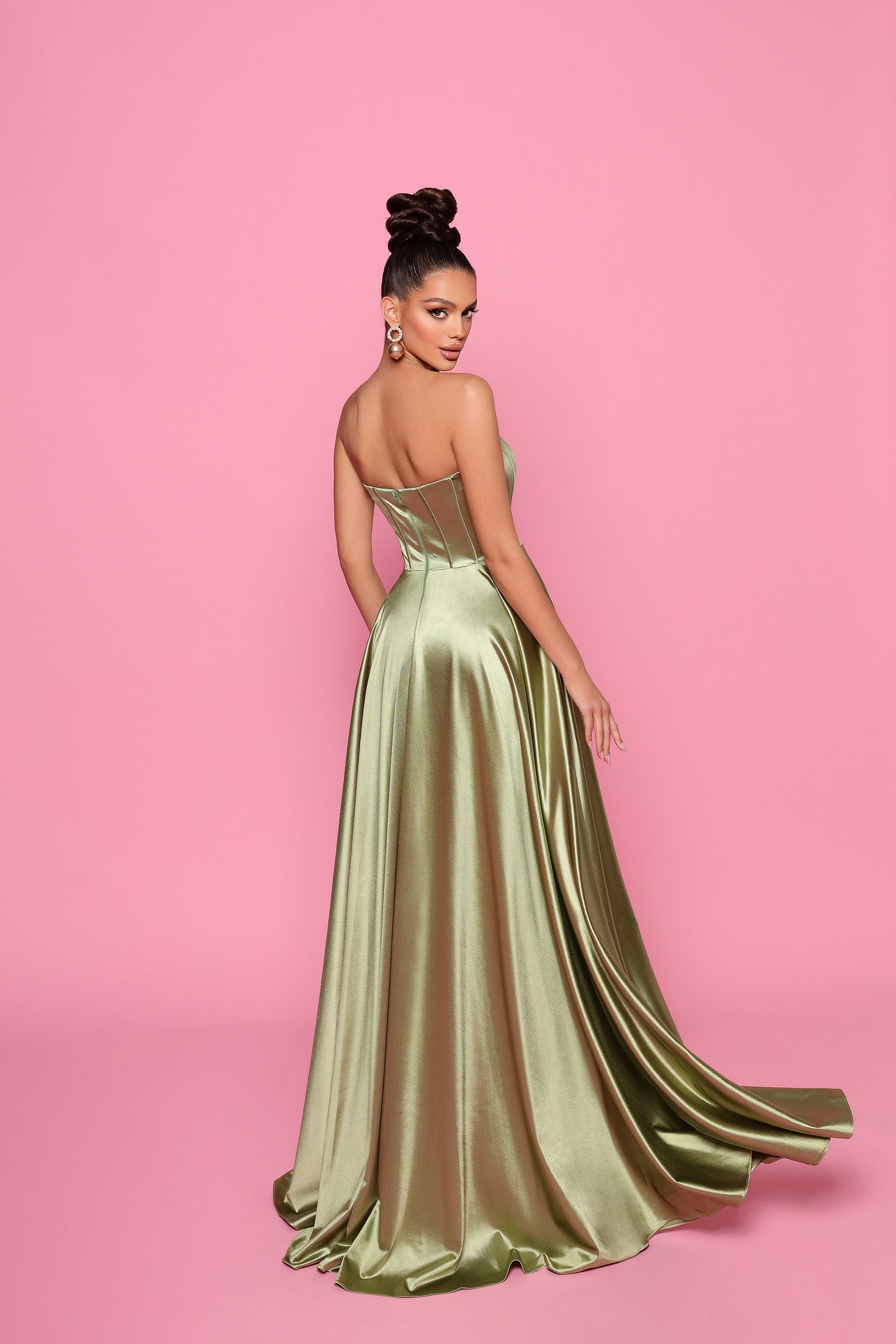 Woman wearing a green evening gown on a pink background