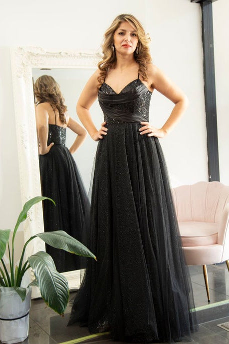 Woman in a black evening gown standing in front of a mirror.