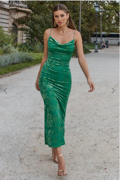 Woman in a green dress walking outdoors on a street.